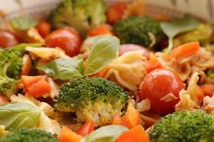 pasta met broccoli, kers tomaten, tonijn vis, basilicum, klok peper foto