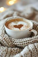 een kop van koffie met een hartvormig ontwerp in de schuim, zittend Aan een wit en bruin gebreid kabelpatroon sjaal. foto