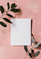 blanco papier Aan een roze achtergrond met eucalyptus bladeren. foto
