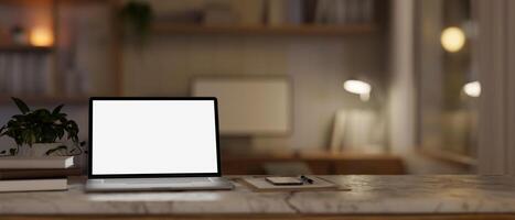 een wit scherm laptop computer mockup Aan een wit marmeren tafel in een knus huis kantoor Bij nacht. foto