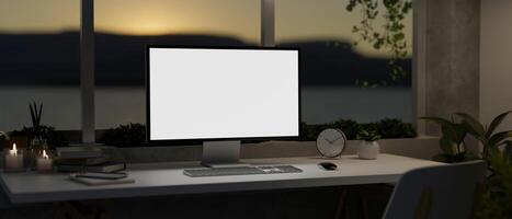 een modern huis kantoor in de avond met een pc computer mockup Aan een tafel tegen de venster. foto