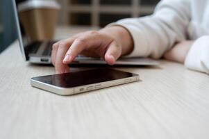 een detailopname beeld van een vrouw aanraken Aan haar smartphone scherm, controle berichten terwijl werken. foto