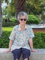 portret van gelukkig ouderen vrouw zittend in park foto