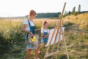 jong moeder en haar dochter hebben plezier, moeder dag. glimlachen moeder met mooi dochter trekt natuur. foto