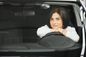 jong vrouw glimlachen in haar nieuw auto in een toonzaal foto