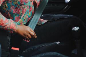 donker bruin huid Afrikaanse vrouw hand- knikken veiligheid riem in de auto voor auto- ongeluk veiligheid concept foto