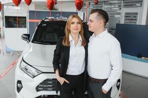 jong mooi gelukkig paar buying een auto. man buying auto voor zijn vrouw in een salon. auto boodschappen doen concept foto