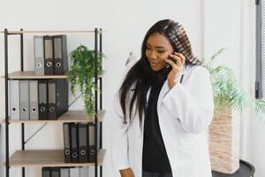 glimlachen vrouw dokter gebruik makend van mobiel telefoon in de ziekenhuis. foto