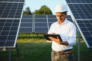 portret van een jong Indisch mannetje ingenieur of architect Bij een zonne- paneel boerderij. de concept van schoon energie foto