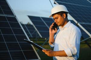 een Indisch mannetje ingenieur werken Aan een veld- van zonne- panelen. de concept van hernieuwbaar energie foto