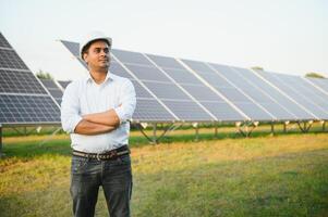 een Indisch mannetje ingenieur werken Aan een veld- van zonne- panelen. de concept van hernieuwbaar energie foto