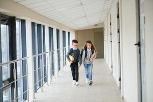 schattig leerlingen rennen naar beneden de hal Bij de elementair school- foto