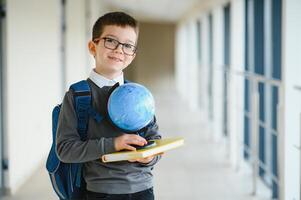 gelukkig schattig knap jongen in bril met school- zak en boek in zijn hand. eerste tijd naar school. terug naar school. foto