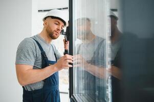 knap jong Mens installeren baai venster in nieuw huis bouw plaats foto