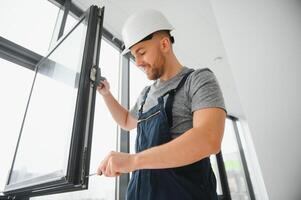 werkman in overall installeren of aanpassen plastic ramen in de leven kamer Bij huis foto