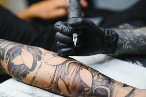 tatoeëerder met zijn machine tatoeëren Aan de arm met de ontwerp getrokken, concept van kunst en ontwerp foto