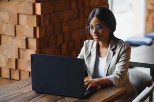 gefocust jong Afrikaanse Amerikaans zakenvrouw of leerling op zoek Bij laptop, echt zwart vrouw werken of aan het studeren met computer aan het doen Onderzoek of voorbereidingen treffen voor tentamen online foto