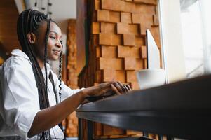 gefocust jong Afrikaanse Amerikaans zakenvrouw of leerling op zoek Bij laptop, echt zwart vrouw werken of aan het studeren met computer aan het doen Onderzoek of voorbereidingen treffen voor tentamen online foto