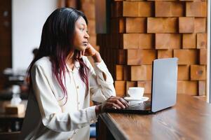 gefocust jong Afrikaanse Amerikaans zakenvrouw of leerling op zoek Bij laptop, echt zwart vrouw werken of aan het studeren met computer aan het doen Onderzoek of voorbereidingen treffen voor tentamen online foto