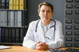 portret van volwassen vrouw dokter in wit jas Bij werkplaats foto