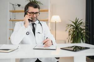 portret van senior dokter zittend in medisch kantoor. foto