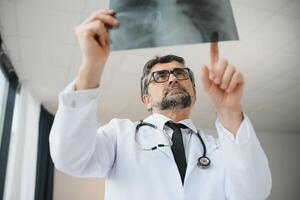 ouder Mens dokter onderzoekt röntgenstraal beeld van longen in een kliniek foto