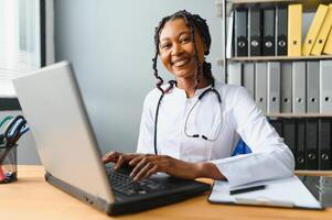 gezondheidszorg, medisch en technologie concept - Afrikaanse vrouw dokter met laptop foto