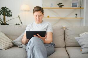 mensen, technologie en internet concept - gelukkig midden- oud vrouw met tablet pc computer Bij huis. foto