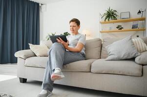 mensen, technologie en internet concept - gelukkig midden- oud vrouw met tablet pc computer Bij huis. foto