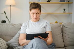 mensen, technologie en internet concept - gelukkig midden- oud vrouw met tablet pc computer Bij huis. foto