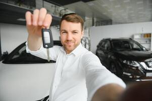 jong Mens is kiezen een nieuw voertuig in auto handel en maken foto Aan een smartphone.