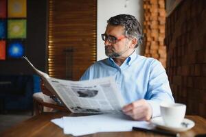 koffie pauze. Mens drinken koffie en lezing krant- in cafe bar foto