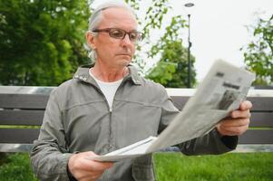 oud grijs haar Mens rust uit Aan de bank in zomer park foto