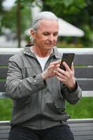 oud grijs haar Mens rust uit Aan de bank in zomer park foto