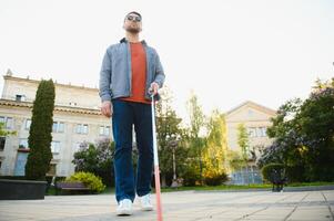 Blind Mens wandelen Aan trottoir Holding stok foto