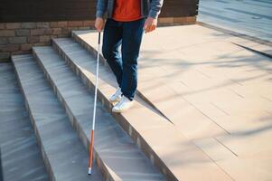 Blind Mens wandelen Aan trottoir Holding stok foto