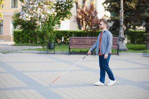 Blind Mens wandelen Aan trottoir Holding stok foto