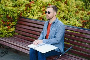 Blind Mens lezing braille boek, zittend Aan bank in zomer park, resting foto