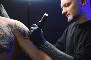 tatoeëren artiest handen vervelend handschoenen en Holding een tatoeëren machine foto