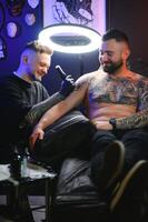 professioneel tatoeëren artiest maakt een tatoeëren Aan een jong Mens hand- foto