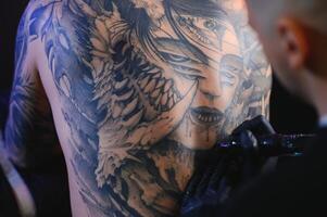 schot van een tatoeëren artiest handen vormen perfect lijnen Aan Mens terug met inkt foto