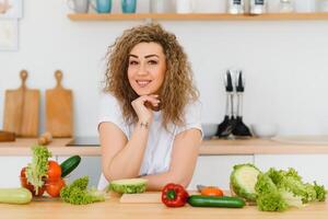 gelukkig jong huisvrouw menging groente salade foto