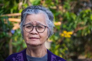 portret van een gelukkig ouderen vrouw glimlachen in haar tuin. foto