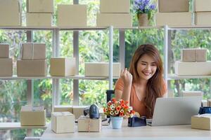 Aziatisch zakenvrouw vervelend gewoontjes kleding op zoek Bij de laptop en glimlach terwijl zittend Aan een stoel in de kantoor. ruimte voor tekst. concept bedrijf en e-commerce foto