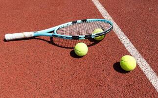 racket met een tennis bal Aan een rood klei rechtbank. foto