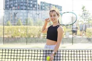 tiener- tennis speler vrouw Aan rechtbank met racket foto