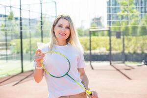 schoonheid sport. mooi jong vrouw in geschiktheid kleren. slank lichaam. kijken Bij camera. badminton oefening. macht welzijn. training levensstijl. opleiding positie. foto