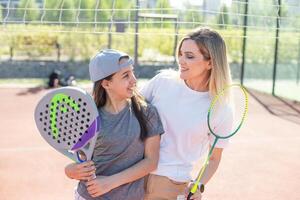 gelukkig Kaukasisch moeder en dochter spelen padel tennis en badminton Aan tennis rechtbank buitenshuis foto