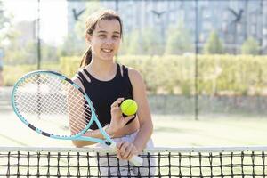 tiener- tennis speler vrouw Aan rechtbank met racket foto