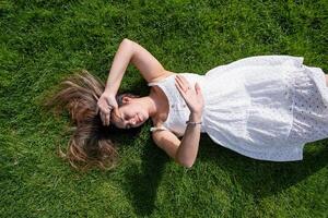 mooi jong vrouw aan het liegen Aan groen gras foto